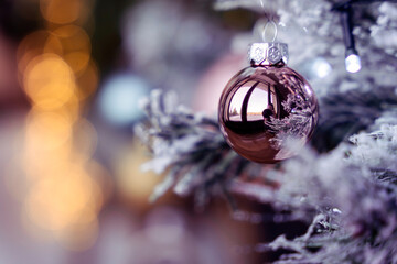 Rose gold pink glass Christmas ball bauble, snowy tree branch, bokeh bg