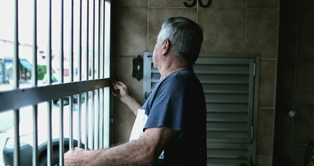 Old man arriving home, sliding metal garage gate. Senior entering house, casual