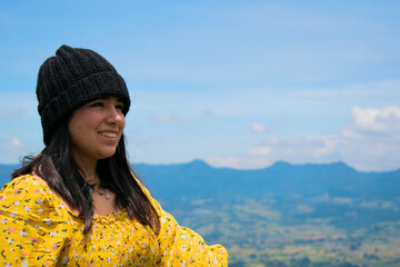 Mujer con sommbrero y blusa amarilla mirando el horizonte y sonriendo en un paisaje natural con un...