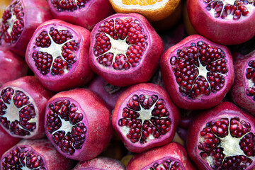 Cut pomegranates on counter with street fresh juice. Red and orange fruits, front view. Real showcase with street food in Istanbul, Turkey