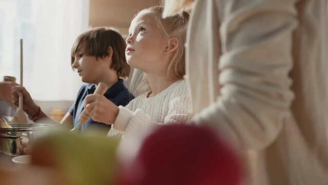 Close up of cute son and daughter learn how to cook omlet, having fun, helping parents in the kitchen. Caucasian family with little kids prepare breakfast together at home.