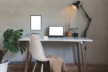 Home office with laptop and chair, book on desk decor white frame as lamp light and monstera tree pot, plants house with wall loft style interior decorations workspace.