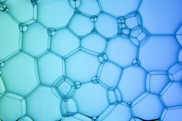 The surface of the bubbles. Extreme close-up of transparent soap foam structure on green and blue....
