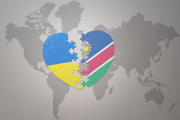 puzzle heart with the national flag of ukraine and namibia on a world map background. Concept.