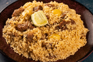 Spicy beef biryani in plate with lemon on marble background top view of indian and pakistani food