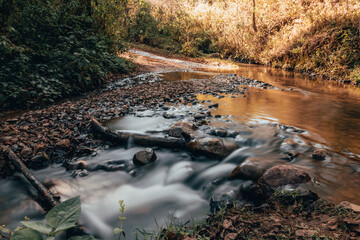 River in the mountains with vegetation, the ocher color of autumn fades with that of sunset, the...