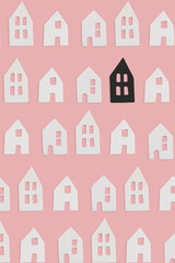 White and one black small decor ceramic houses with windows on pink flat lay background. Minimal creative card or wallpaper idea. Top view pattern. Stand out concept.