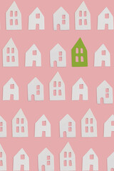 White and one green small decor ceramic houses with windows on pink flat lay background. Minimal creative card or wallpaper idea. Top view pattern. Stand out concept.