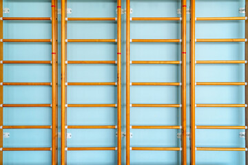 Wooden wall bars background stands in empty school gym front view. Sport training concept.