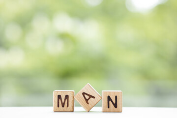 Man - word is written on wooden cubes on a green summer background. Close-up of wooden elements.