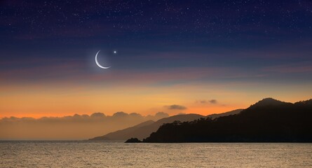 Ramadan background with crescent, stars in glowing sky above mountains and sea.