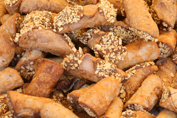 biscuits called cannoli filled with chocolate and above the chopped toasted almonds and hazelnuts for sale in the pastry stall