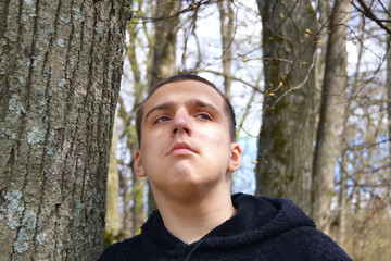 A young autistic guy in the park walks among the trees