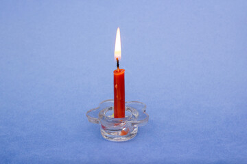 a small orange candle burns on a blue background