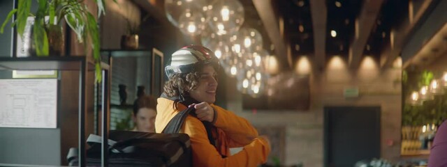 Food delivery courier in bicycle helmet entering the restaurant to pick up order for delivery. Shot with 2x anamorphic lens