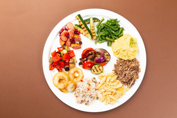 Various side dishes in a dish. Vegetables, mashed potatoes, french fries, pasta.