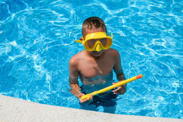 A child in a mask for swimming. A young boy are engaged in diving in the pool.