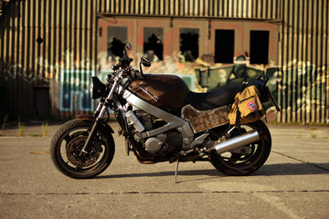 Obraz na płótnie Canvas Altes rostiges Motorrad vor verlassener Lagerhalle