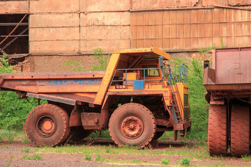 Obraz premium Decommissioned quarry trucks awaiting disposal. Iron ore mining equipment at the end of its useful life.