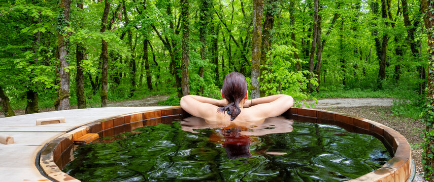Woman in nordic bath in front of a forest.