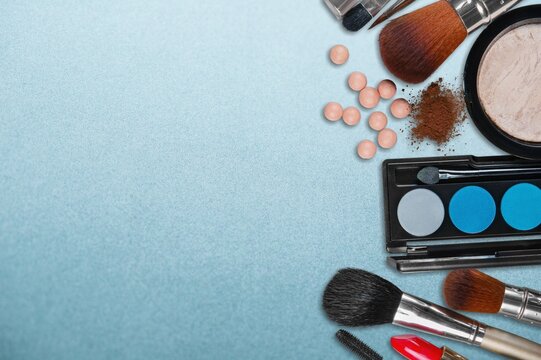 Different Makeup artist's tools on blue marble table: brushes for powder, blush, eyebrows.