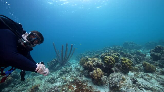 Professional diver, undersea cinematographer filming a self-portrait in coral reef of Caribbean Sea around Curacao