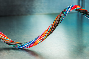 Swirl of multicolored electrical computer cable on metallic background