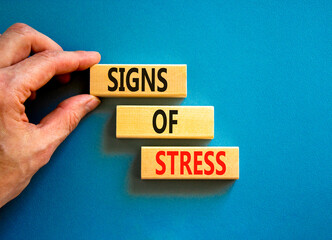 Signs of stress symbol. Concept words Signs of stress on wooden blocks. Beautiful blue table blue background. Doctor hand. Psychological business and signs of stress concept. Copy space.