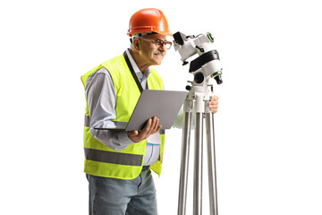 Geodetic surveyor measuring with a positioning station and holding a laptop computer