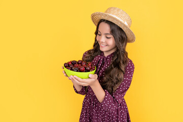 smiling teen child hold cherry bowl on yellow background