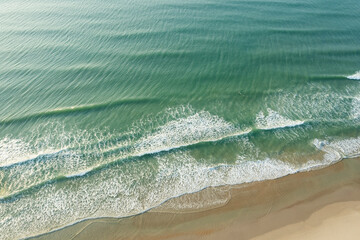 Aerial view of waves breaking and sandy shoreline along a North Carolina beach. Beach vacation from...