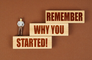 On wooden blocks with the inscription - REMEMBER WHY YOU STARTED, there is a miniature figure of a...