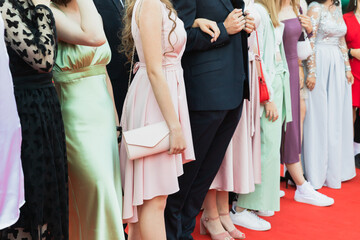 Prom guests standing on a red carpet, close up