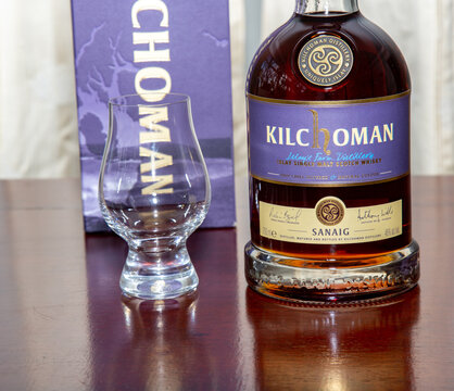 Bras&iacute;lia, DF, Brazil, May 19, 2022: Kilchoman Sanaig single malt peated Scotch whisky on the rustic wooden table with malted and peated sevada seeds. Man Whisky in selective focus