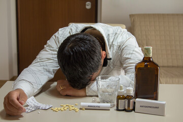 Image of a man sleeping with his head resting on the table after abusing alcohol, anxiolytics and...