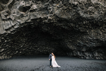 Groom kiss the bride in the huge basalt cave on the Black Sand beach in Vic, Island. Elopement, Wedding
