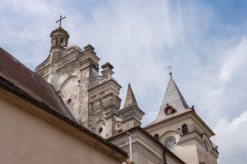 Fototapeta na wymiar Old Catholic Church on blue sky background. Baroque sacral architecture. Ukraine