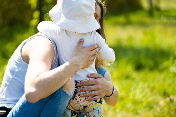 mother hugs baby girl at sunny summer day, mother hands - obrazy, fototapety, plakaty
