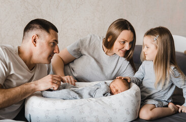 Portrait of loving family with newborn son and infant daughter. Happy caucasian family of four people. Sister meets her newborn brother. Selective focus. Film grain