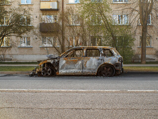 Side view to the burned car on the street during the day on district environment. Selective focus on vehicle.