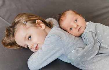 Portrait of newborn boy and infant girl. Loving siblings. Sister meets her newborn brother. Selective focus. Film grain