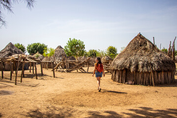 Woman walking between houses of the Karo tribe in southern Ethiopia, Omo Valley