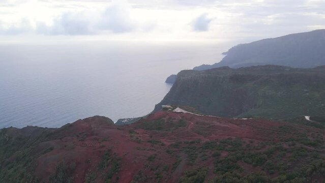 Aerial view of stunning viewpoint Mirador de Abrante with glass observation balcony above Agulo village in La Gomera island at sunrise. Restaurant on red clay