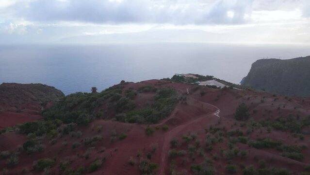 Aerial view of stunning viewpoint Mirador de Abrante with glass observation balcony above Agulo village in La Gomera island at sunrise. Restaurant on red clay