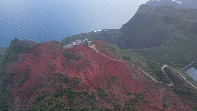 Aerial view of stunning viewpoint Mirador de Abrante with glass observation balcony above Agulo village in La Gomera island at sunrise. Restaurant on red clay