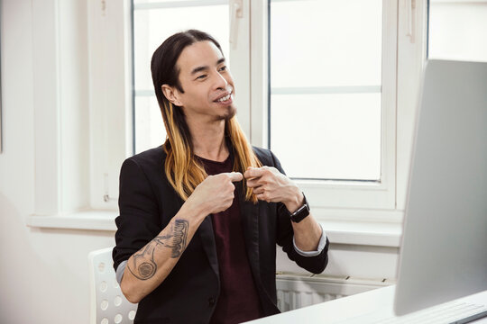 Mid adult man using sign language in front of computer
