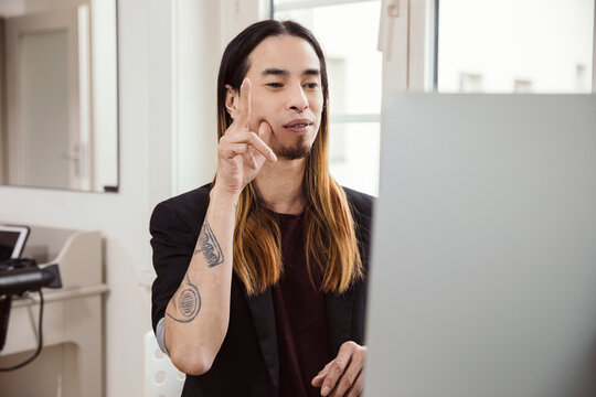 Mid adult man using sign language in front of computer