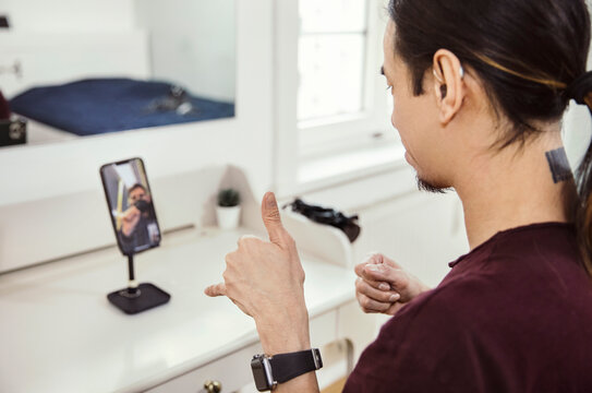 Mid adult man using sign language in front of smartphone