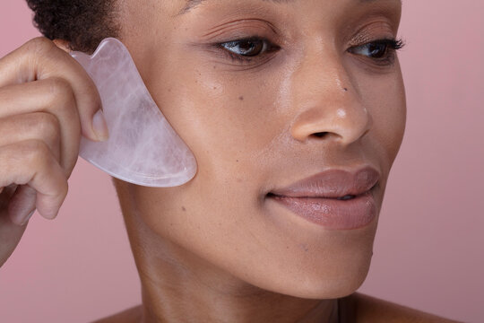 Close-up of woman massaging face with rose quartz guasha