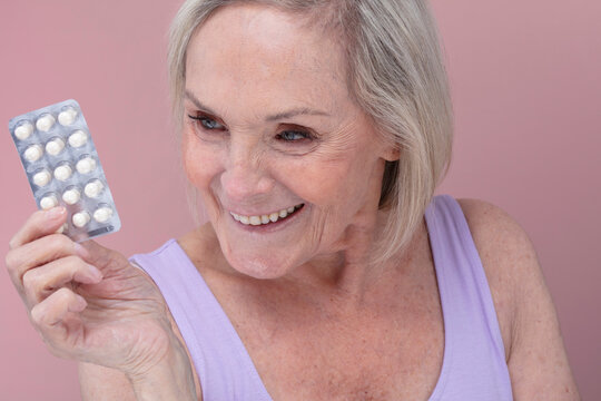 Studio shot of smiling senior woman holding blister pack with tablets